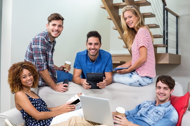 Felizes jovens amigos usando modernas tecnologias no sofá