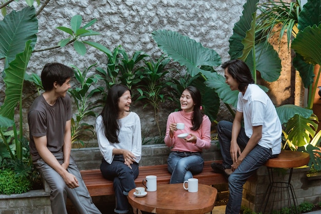 Felizes jovens conversando sentados na mesa e no banco de madeira da horta