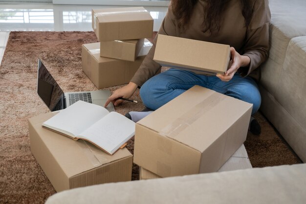 Felizes jovens empresários asiáticos estão organizando caixas para entregar produtos aos clientes.