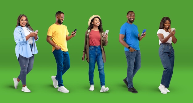 Felizes jovens mulheres e homens afro-americanos em digitação casual em smartphones navegando na internet