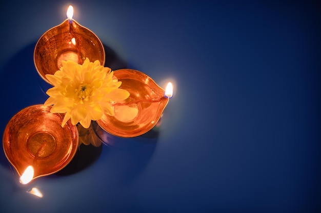 Felizes lâmpadas de óleo Diwali Diya e flores amarelas sobre fundo azul Celebrando o tradicional feriado indiano de luz