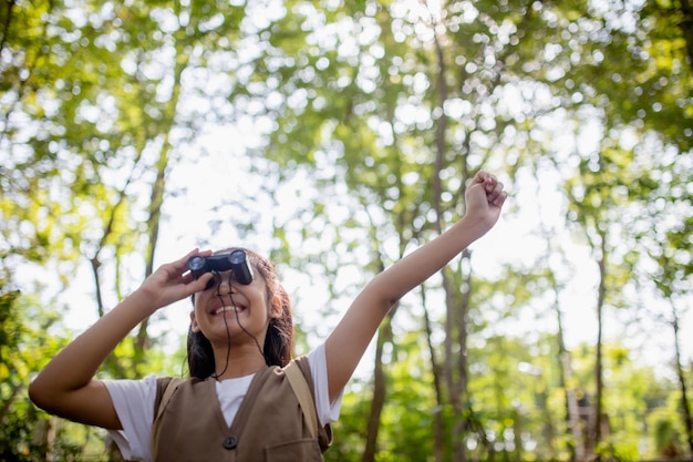 Foto felizes meninas asiáticas olhando para frente e sorrindo criança com os binóculos no parque conceito de viagem e aventura férias de liberdade