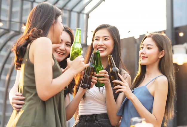 Felizes mulheres asiáticas segurando garrafas de cerveja