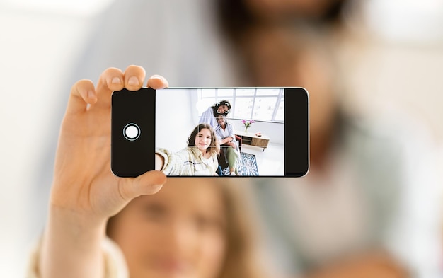 Foto felizes mulheres maduras e adolescentes europeias fazem fotos na tela do smartphone na sala de estar branca