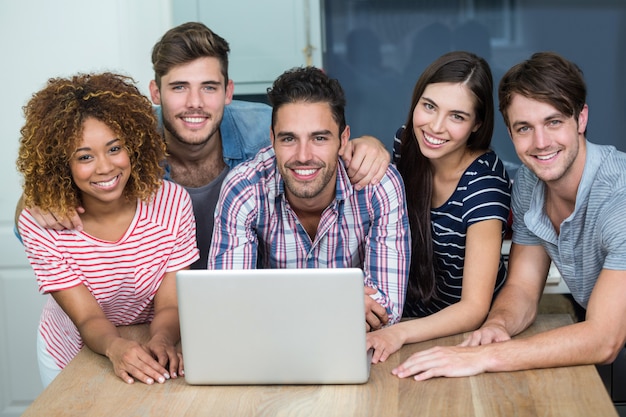 Felizes multi étnica amigos usando o laptop na mesa em casa