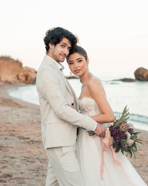 Felizes recém-casados abraçando no fundo do mar azul Casamento a pé em uma praia de areia No fundo do céu azul