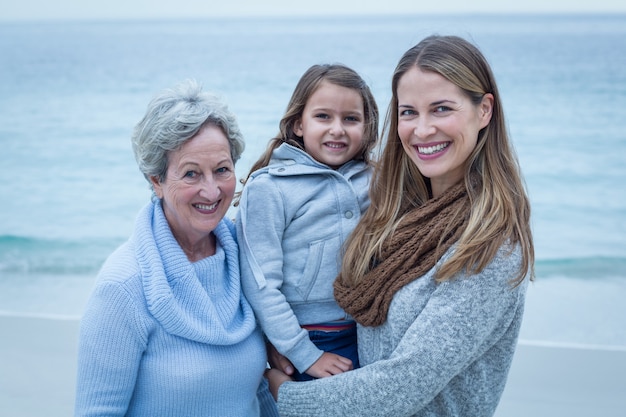 Felizes três gerações de mulheres em pé na praia