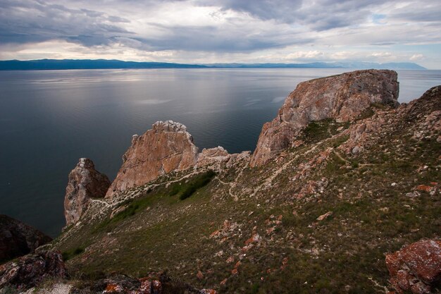 Felsen Drei Brüder auf der Insel Olchon am Baikalsee Himmel mit Wolken Auf den Steinen ist rotes Moos Schöner Himmel es regnet in der Ferne Berge sind sichtbar