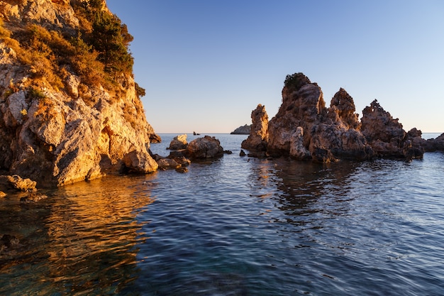 Felsen im Meer spiegeln sich im goldenen Licht der felsigen Küste des Wassers Griechenland