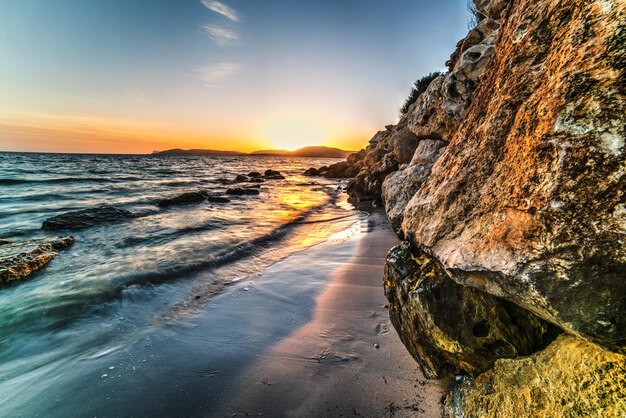 Felsen und Sand am Ufer von Alghero bei Sonnenuntergang