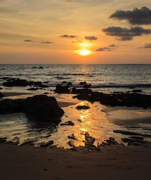 Felsenstrandsonnenuntergang mit goldenen Skylinen