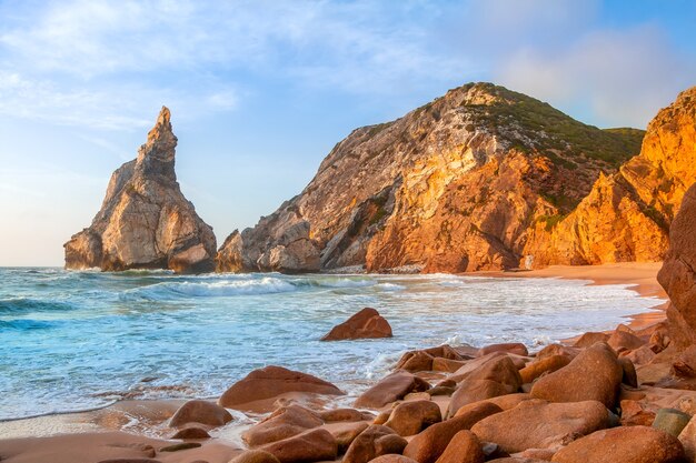 Felsige Küste des Atlantischen Ozeans. Kleiner leerer Strand. Sonnenuntergang malte die Steine golden