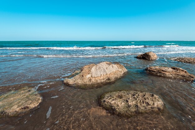 Felsige Meeresküste mit türkisfarbenem Wasser am Strand