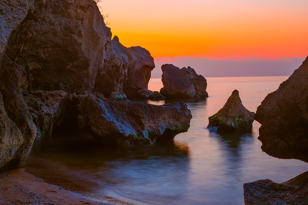 Felsige Meereslandschaft mit bizarren Felsen und Langzeitbelichtung bei Sonnenuntergang