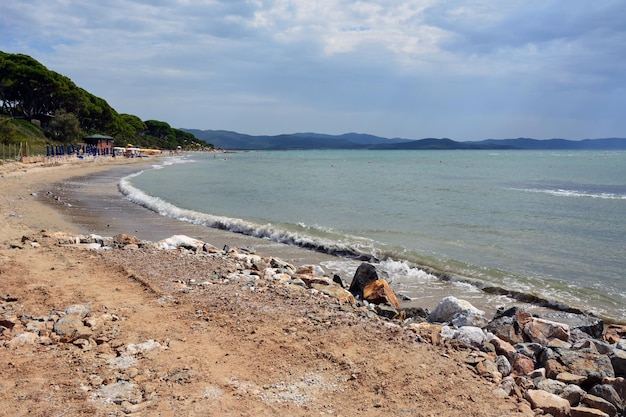 Felsiger Strand am Meer mit Hotelschirmen und Sonnenliegen in der Ferne