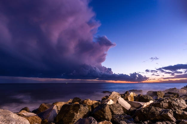 Felsiger Strand bei Sonnenuntergang mit Gewitterwolken