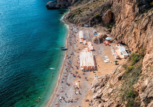 Felsiger Strand mit rosafarbenen Kieseln und kristallklarem azurblauem Meer Konzept des idealen Reiseortes für den Sommer