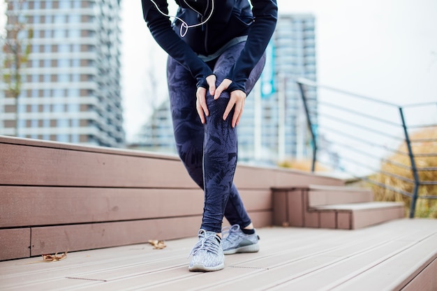 Femanle jogger tiene problemas con la rodilla en el entrenamiento