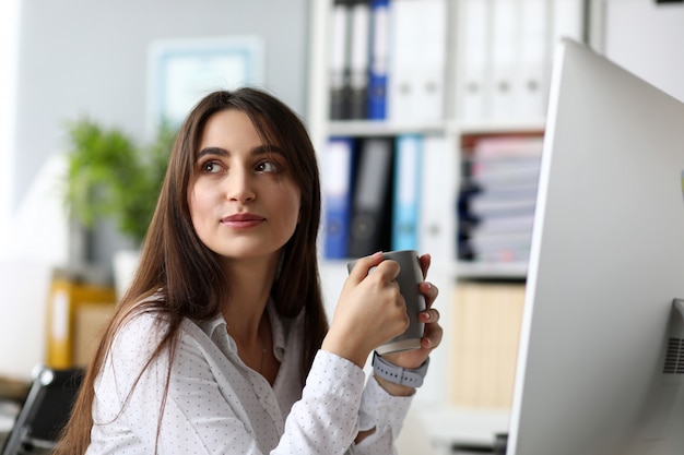 Fêmea alegre positiva sentado na mesa de trabalho água potável