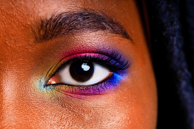 Fêmea com maquiagem de arco-íris e cílios longos em estúdio azul baclground