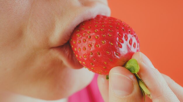 Fêmea comendo morangos frescos fechados Morangos vermelhos em uma mão de mulher Conceito Fruta a chave para uma dieta saudável e figura esbelta