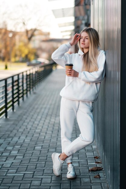 Fêmea de terno esporte branco com café na parede escura