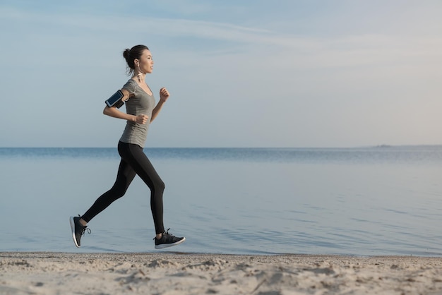 Fêmea fitness fazendo exercício de corrida na praia