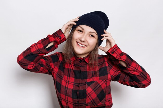 fêmea jovem atraente hipster, boné preto e camisa vermelha, segurando a mão na cabeça