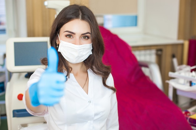 Fêmea jovem médico atraente dentro de casa. Retrato de mulher vestindo uniforme médico na clínica. Médico com equipamento médico. Cosmetologista em sua sala de estar