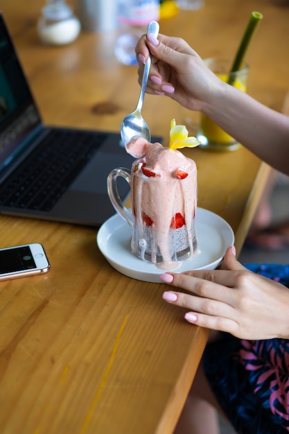 Fêmea nova que trabalha em um portátil, café da manhã saudável com sementes e suco do chia.