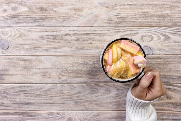 Femininas mãos segurando rosa xícara de café com marshmallow coulorfull