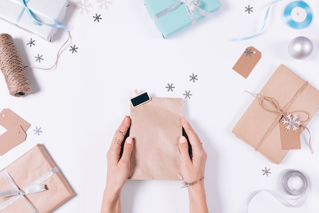 Femininas mãos segurando um pacote com um presente entre as decorações de Natal