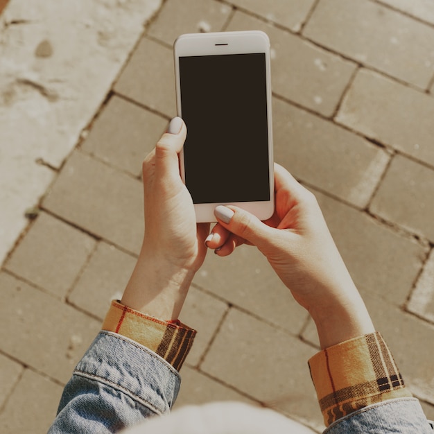 Femininas mãos segurando um smartphone com uma tela em branco