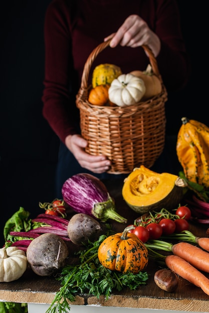 Femininas mãos segurando uma cesta de vime com variedade de legumes