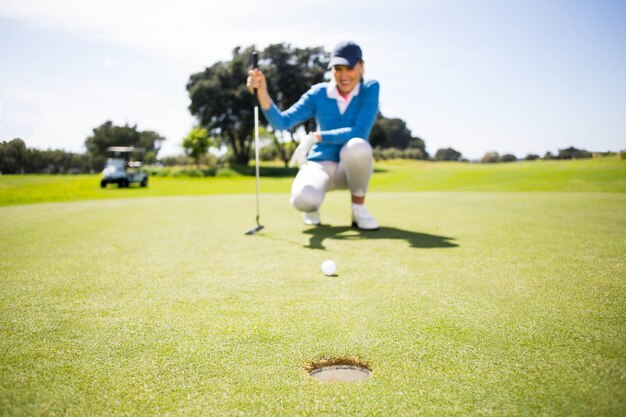 Feminino golfista colocando a bola