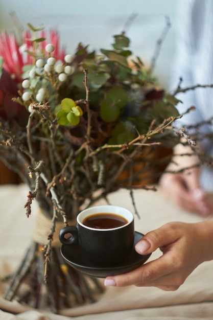 Feminino mão aguenta xícara de café expresso em bouquet exótico