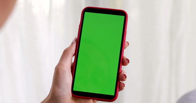 Feminino mão com um smartphone com uma tela verde no branco