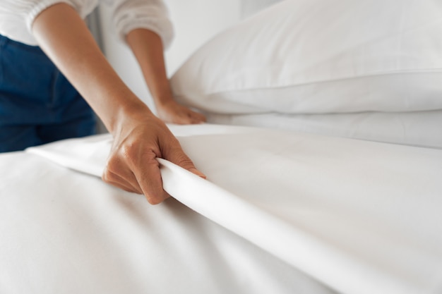 Foto feminino mão configurar lençol branco no quarto