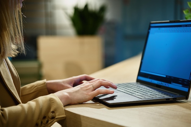 Feminino mão digitando no teclado do laptop no café