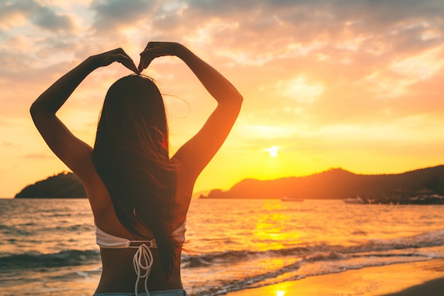 Feminino mão em forma de coração na praia