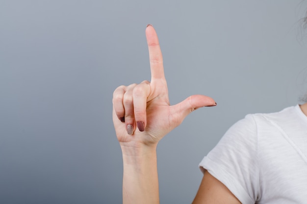 Feminino mão no punho, mostrando dois dedos isolados sobre cinza