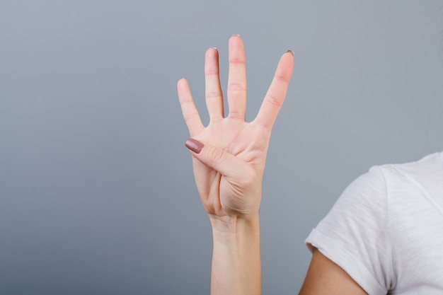 Feminino mão no punho, mostrando quatro dedos isolados sobre cinza