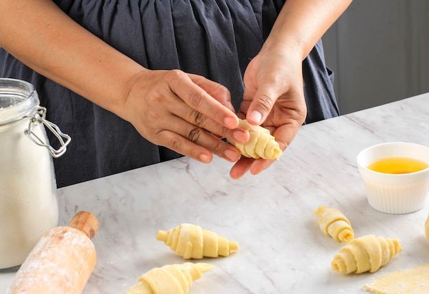 Feminino mão rolling dough em rolos, processo de cozimento fazendo croissant. foco selecionado, conceito para padaria