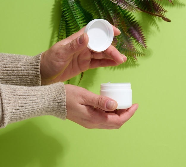 Feminino mão segura o frasco branco vazio para cosméticos. Embalagem para creme, gel, soro, publicidade e promoção de produto, mock up