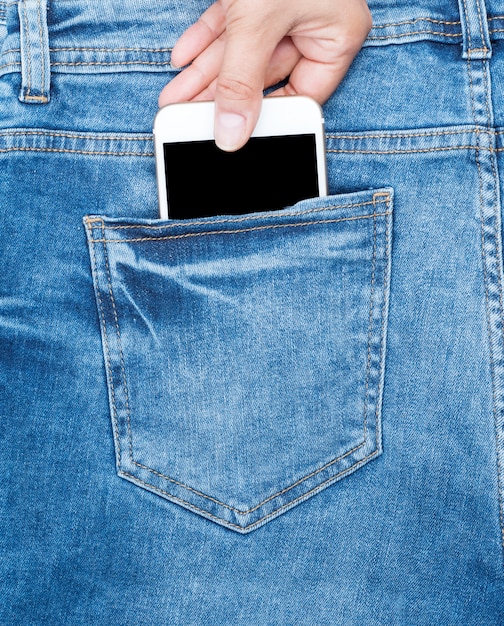 Feminino mão segura um telefone branco na parte de trás do jeans azul