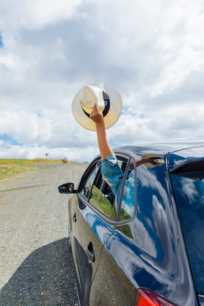 Foto feminino mão segurando o chapéu da janela do carro