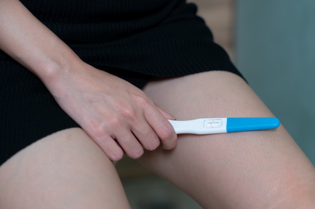 Foto feminino mão segurando o teste de gravidez negativo, com resultados não grávidos.