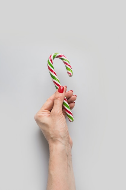 Feminino mão segurando pirulito de cana de doces de Natal. Natal.