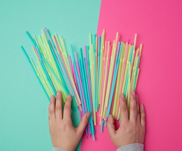 Feminino mão segurando tubos de cocktail plásticos multicoloridos