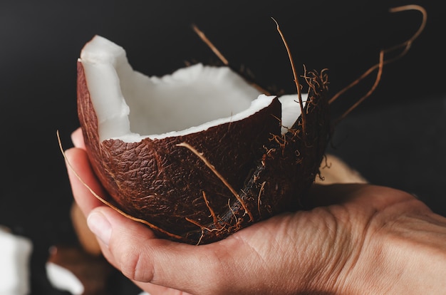 Feminino mão segurando um coco meio preto